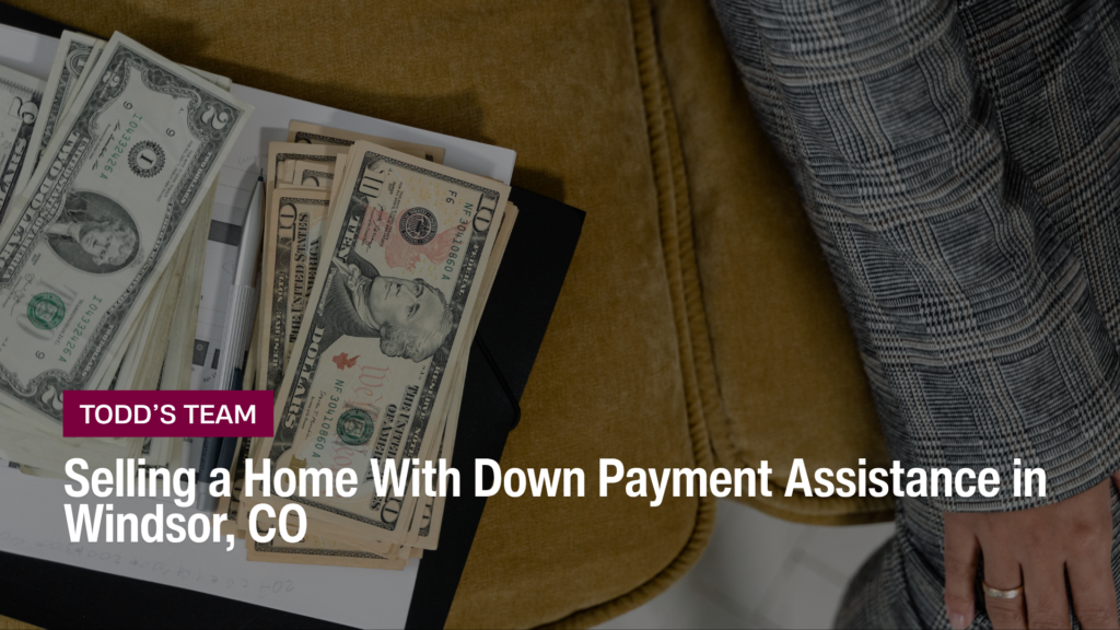 Cash fanned over a notepad and pen beside a person in plaid, selling a home with down payment assistance in Windsor, CO